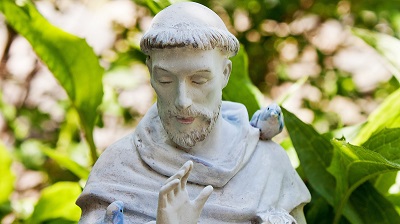 En staty av en harmonisk Franciscus av Assisi med f�glar sittande p� ena axeln och armen.